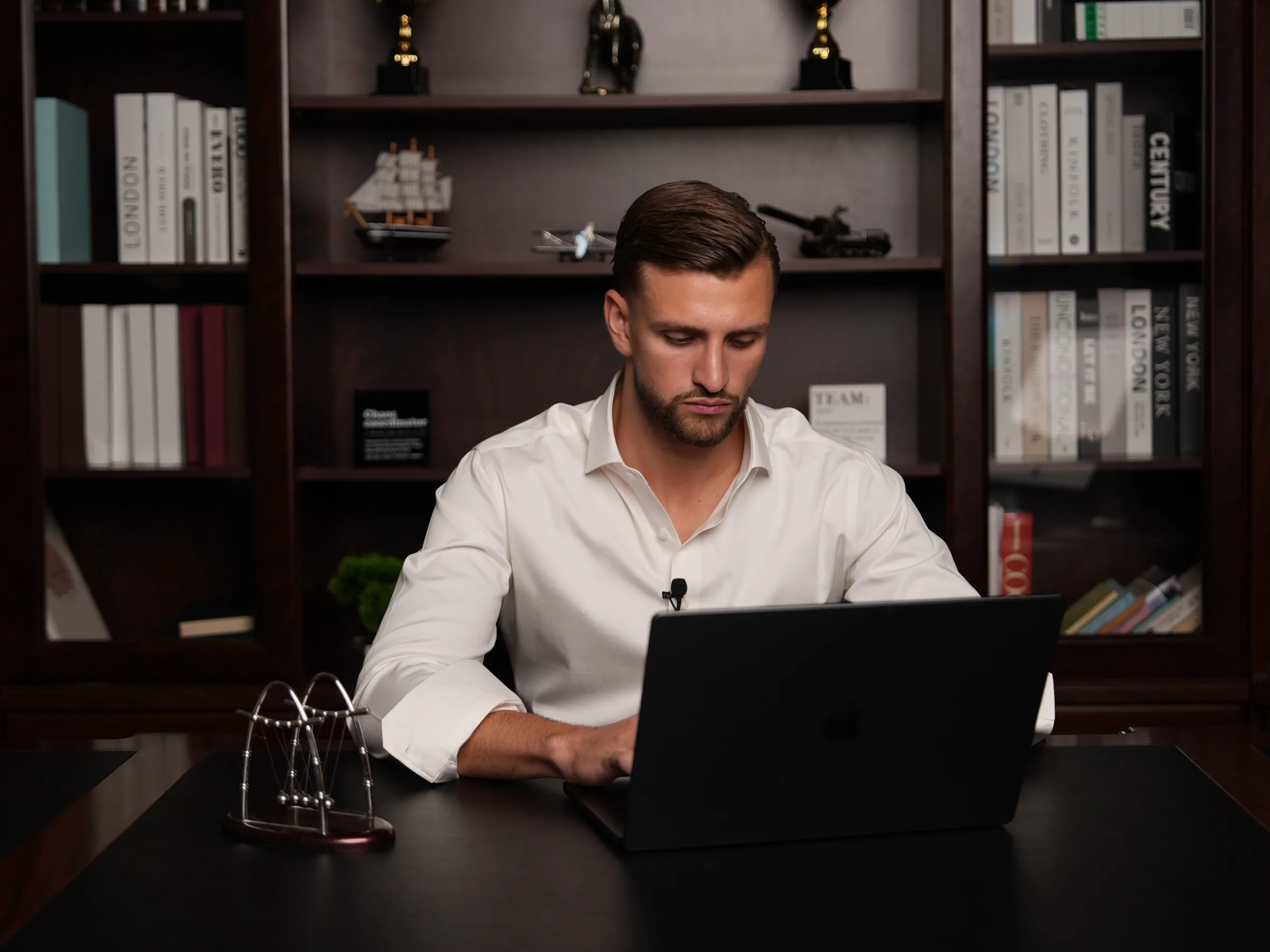 Kilian Kropiunik arbeitet am Laptop vor einem Bücherregal